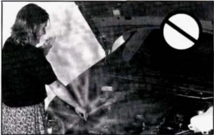 Black-and-white photo of a person working in a car with a large 'no' symbol overlay (no readable text or symbols)