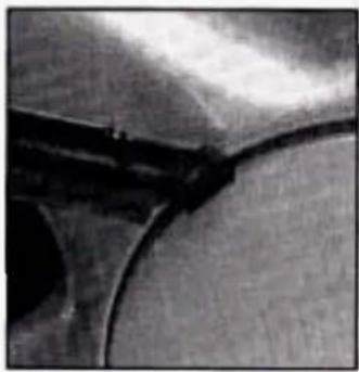 Close-up of a curved metallic object with dark markings, possibly part of a mechanical or architectural component (no visible text or symbols)