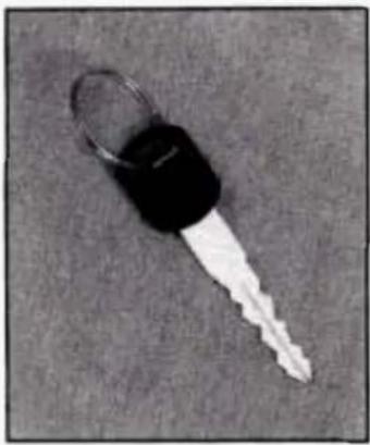 Close-up of a black key with a white handle, lying on a plain gray surface (no text or symbols visible)
