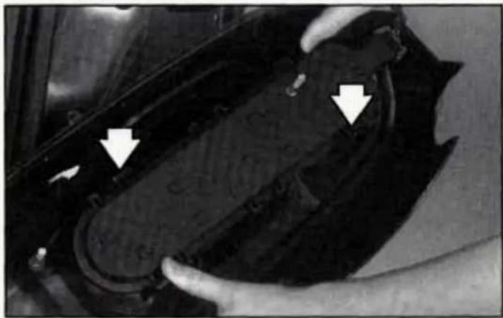 Close-up of hands adjusting a mechanical component with white arrows pointing to features (no visible text or symbols)