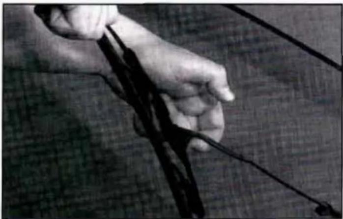 Close-up of hands holding a black bow and string, no visible text or symbols
