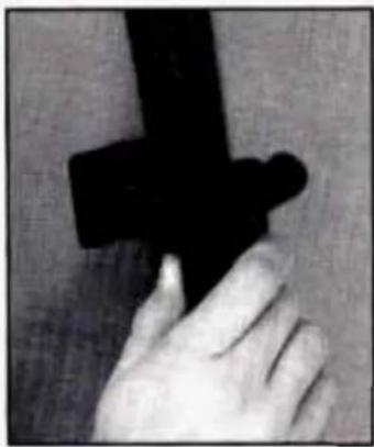 Close-up of a hand holding a black object, possibly a tool or device (no visible text or symbols)
