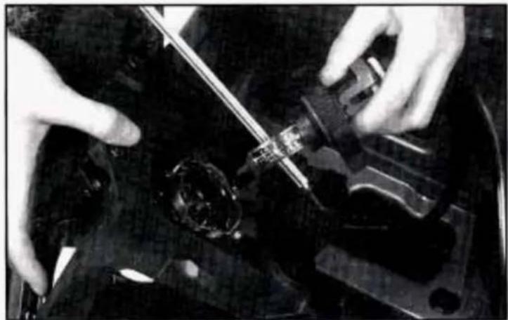 Close-up of hands operating a mechanical device with a tool, no visible text or symbols