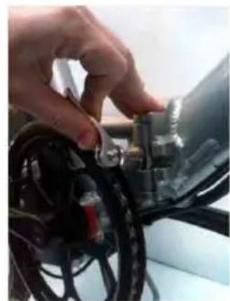 Close-up of a hand adjusting a black automotive component with visible wiring (no text or symbols)