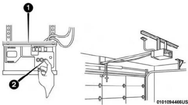 Technical diagram showing installation of a device with labeled components and wiring, including a hand holding a connector.