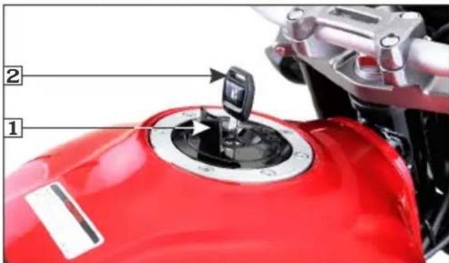 Close-up of a red motorcycle gear shift lever with labeled parts 1 and 2, showing mechanical components and adjustment arrows.