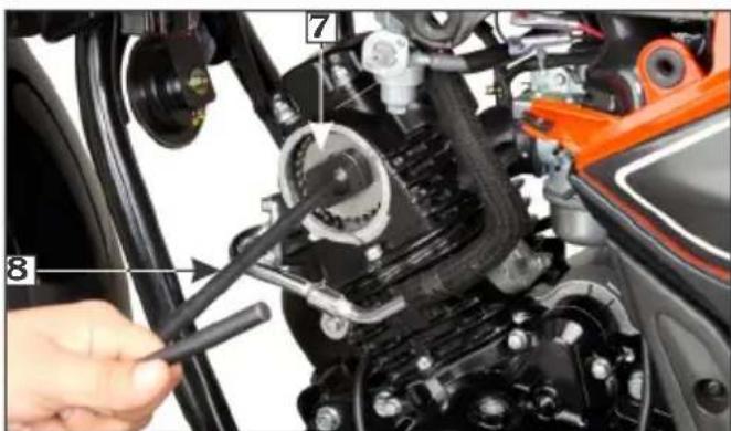Close-up of a car engine component with numbered parts and a hand adjusting the tool, likely for repair or maintenance.