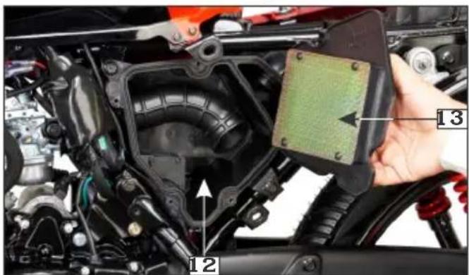 Close-up of a car engine component with numbered parts labeled 12 and 13, showing a hand holding a sensor or sensor module.