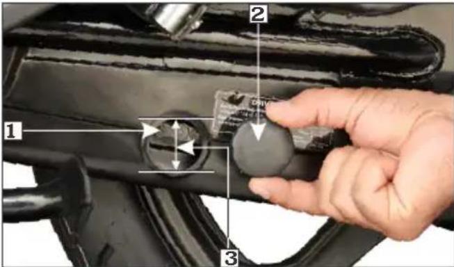 Close-up of a hand adjusting a mechanical component with numbered parts and directional arrows indicating assembly or adjustment.