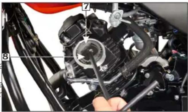 Close-up mechanical assembly diagram with numbered parts and tool interacting with a component