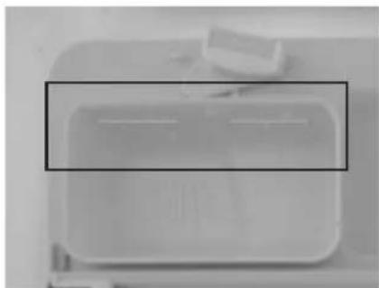 Top-down view of a white rectangular container with two horizontal lines inside, placed on a surface (no text or symbols visible)
