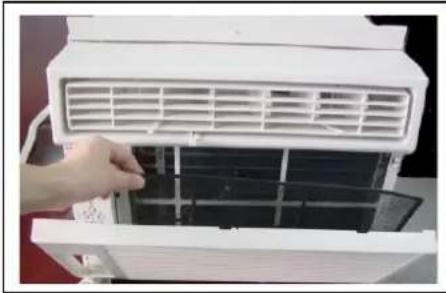 Close-up of a hand installing or adjusting a white air conditioner cover into a stack of black plastic panels (no text or symbols visible)