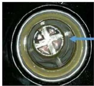 Close-up of a circular mechanical component with a blue arrow pointing to a central feature (no visible text or symbols)
