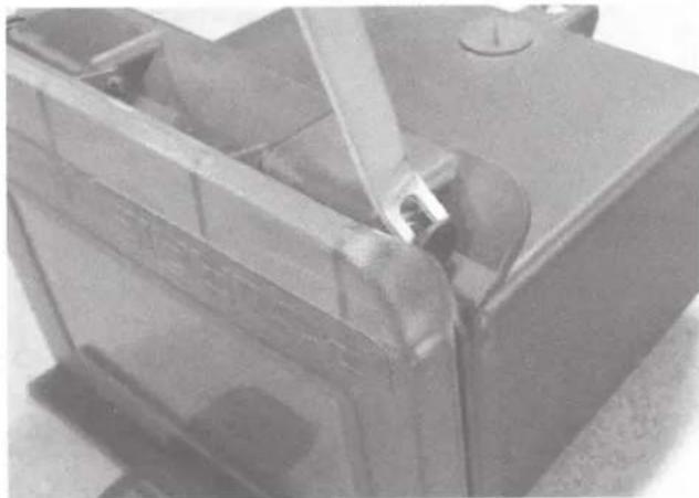 Close-up of a mechanical component with a tool inserted, showing internal components and mounting holes (no visible text or symbols)