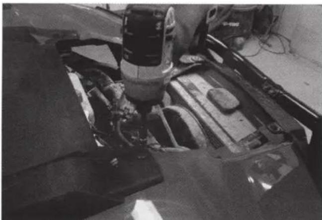 Close-up of a robotic arm operating on a vehicle chassis (no visible text or symbols)