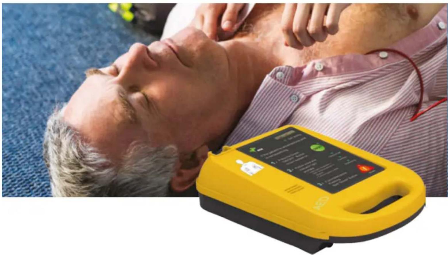 Person lying on back with hands performing CPR on the chest, next to a yellow E2P diagnostic device (no visible text or symbols)