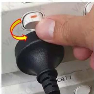 Close-up of a finger pressing a black rubber plug with a yellow arrow indicating rotation (no text or symbols visible)