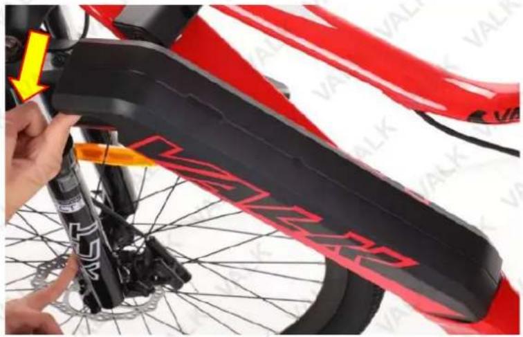 Close-up of a red and black bicycle wheel with visible branding and a yellow arrow indicating a adjustment or repair point (no text or symbols on the main subject)