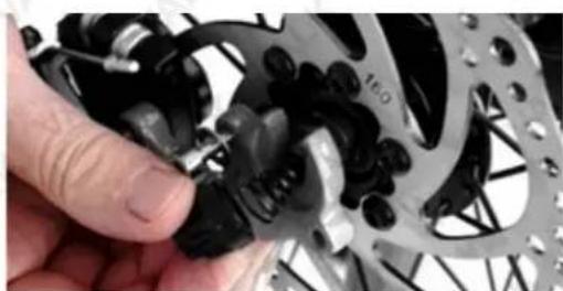 Close-up of a hand adjusting a mechanical gear assembly with visible springs and bolts (no text or symbols)