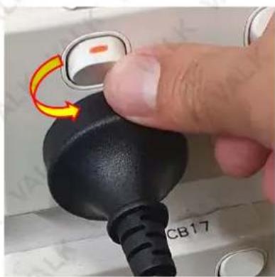 Close-up of a finger pressing a black plug with a yellow arrow indicating rotation (no text or symbols visible)