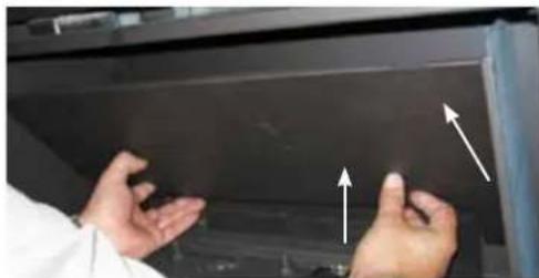 Close-up of hands installing or adjusting a dark panel with white arrows pointing to specific components (no text or symbols visible)