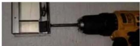 Close-up of a drill bit being inserted into a plastic enclosure, with a black drill bit visible (no text or symbols)