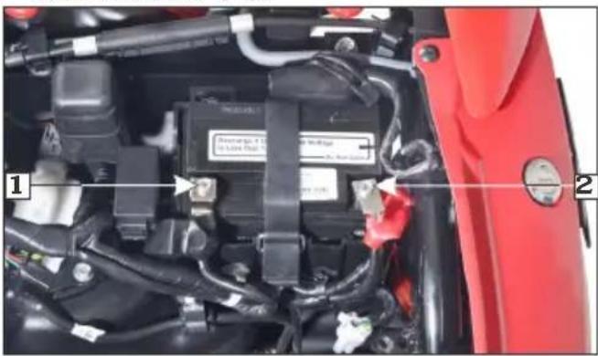 Close-up of a car engine bay with labeled components and wiring, showing numbered parts 1 and 2.