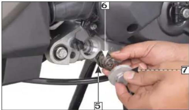 Close-up of a hand adjusting a mechanical component with numbered parts labeled 5, 6, and 7.