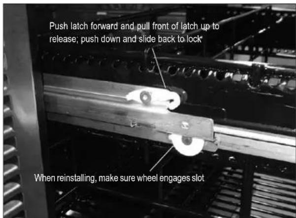 Push latch forward and pull front of latch up to release; push down and slide back to lock When reinstalling, make sure wheel engages slot