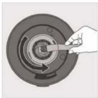 Hand holding a tool interacting with a circular mechanical component (no text or symbols visible)