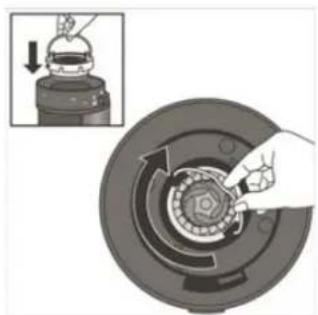 Mechanical assembly diagram showing a hand turning a component on a circular base with arrows indicating motion (no text or symbols)