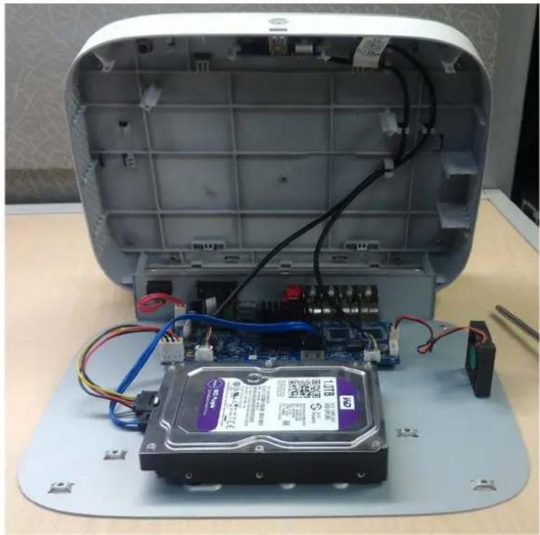 Interior view of an open electronic device showing a hard drive with internal circuit board and wiring (no visible text or symbols)