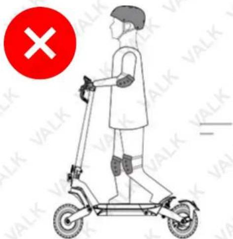 Illustration of a person using an electric scooter with a red circle containing a 'X' symbol and partial text 'VALK' visible on the right.