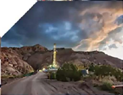 Desert landscape with oil rig and surrounding hills under a dramatic cloudy sky (no text or symbols visible)
