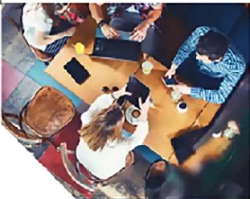 Overhead view of a busy café with patrons seated at a table, no visible text or signage
