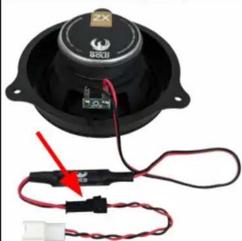 Close-up of a speaker with exposed audio components and wiring, no visible text or symbols