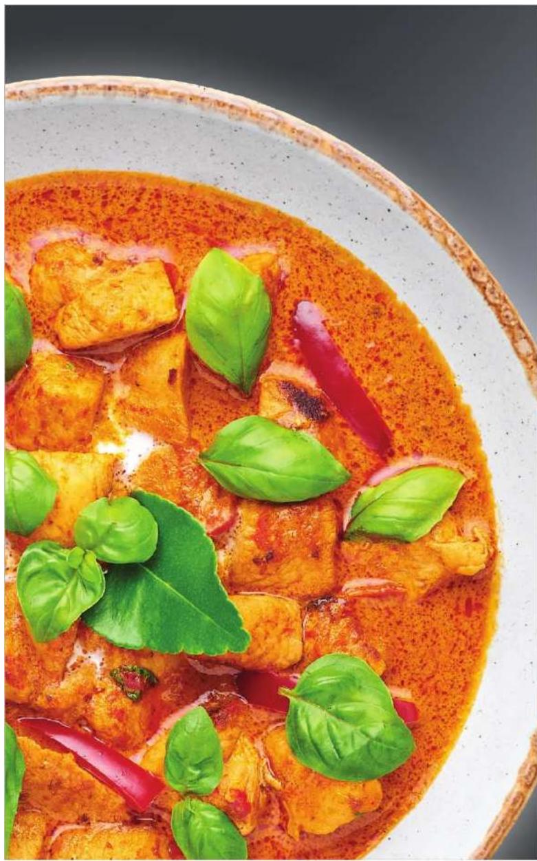 Close-up of a bowl of stewed tofu with green leafy greens and red chili peppers (no text or symbols visible)