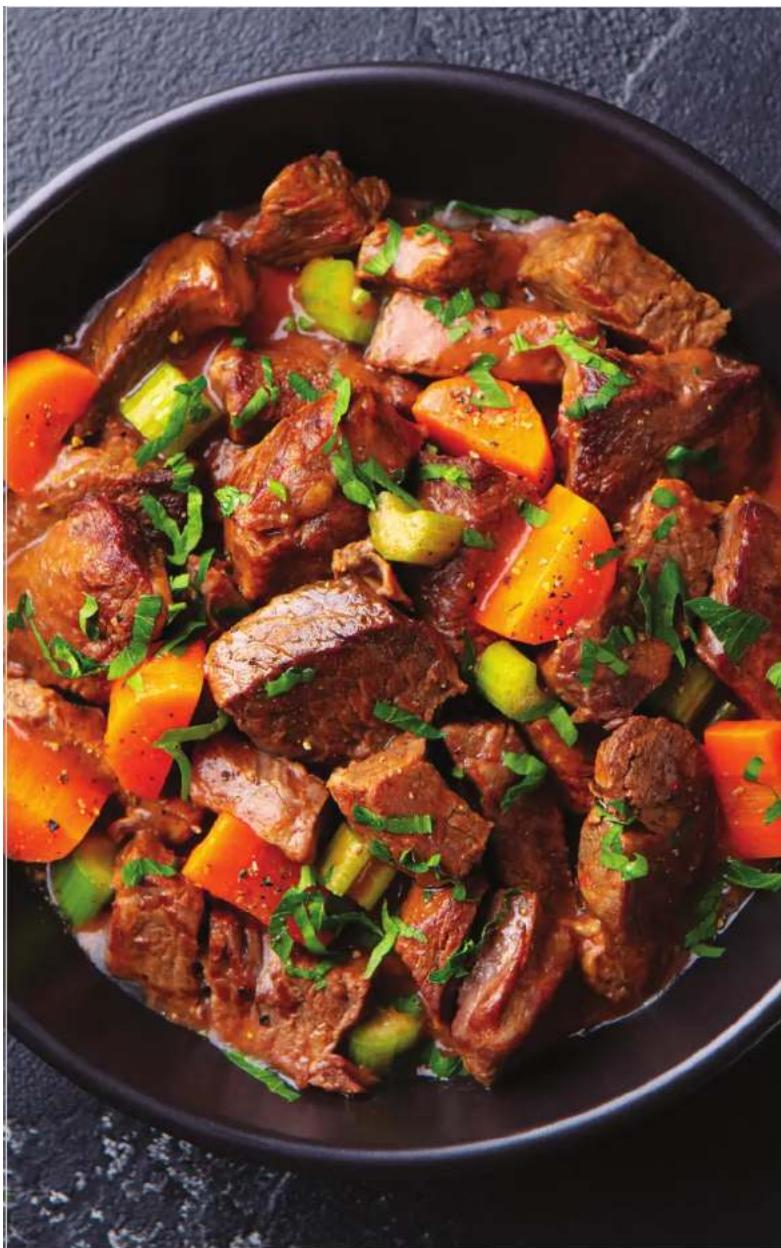 Close-up of a savory meat dish with carrots, peppers, and greens in sauce, served in a black bowl (no text or symbols visible)