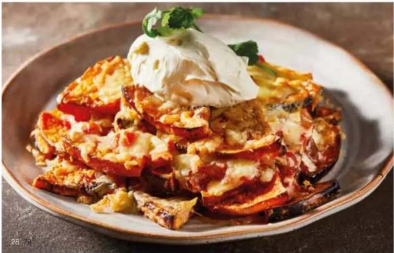 Close-up of a plated dish featuring sliced eggplant topped with whipped cream and garnished with herbs.
