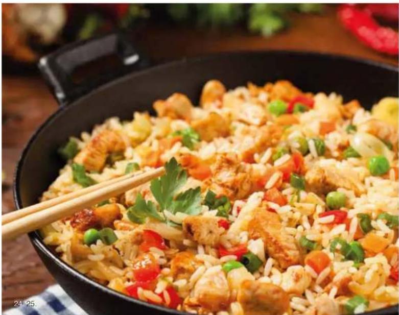 Close-up of a stir-fried dish with chicken, carrots, and green peppers served in a black wok.
