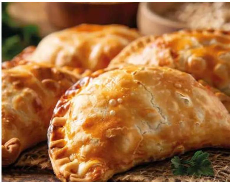 Close-up of golden-brown baked parpatty flaky pastries on a woven mat, garnished with parsley.