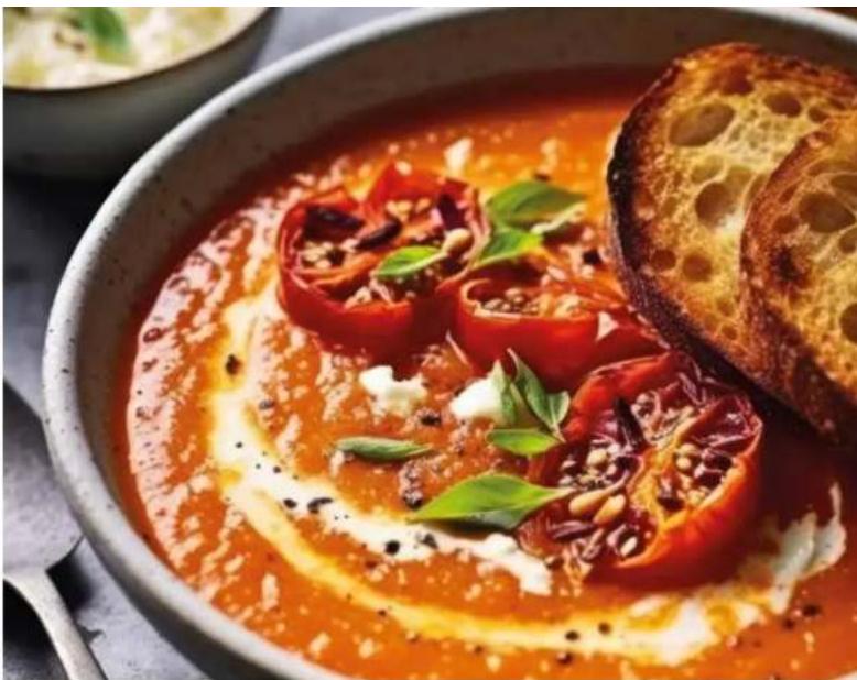 Close-up of a bowl of tomato sauce with sesame seeds and herbs, served with a slice of bread.