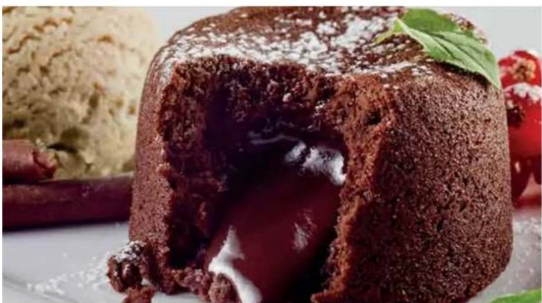 Close-up of a chocolate-shaped dessert with visible chocolate and white cream, surrounded by cinnamon sticks and mint leaves (no text or symbols)