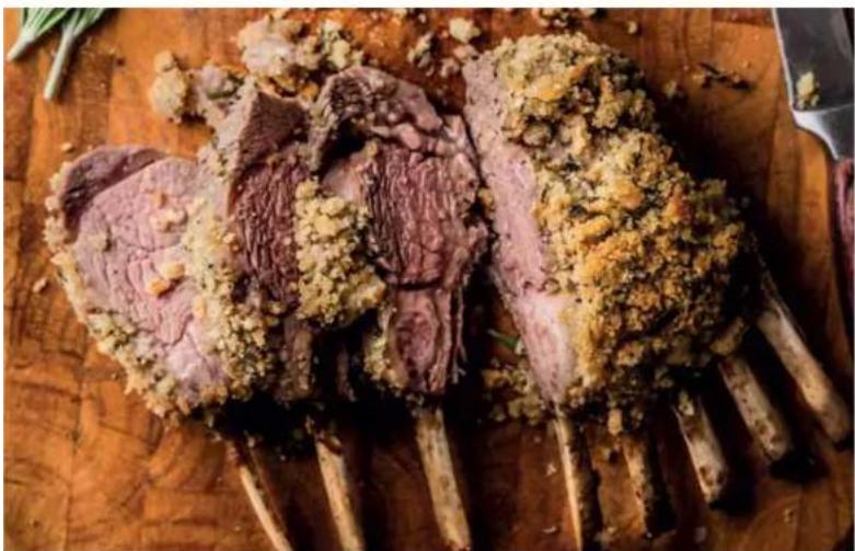 Steamed cut of raw lamb on a wooden cutting board, garnished with powdered sugar and herbs (no text or symbols visible)