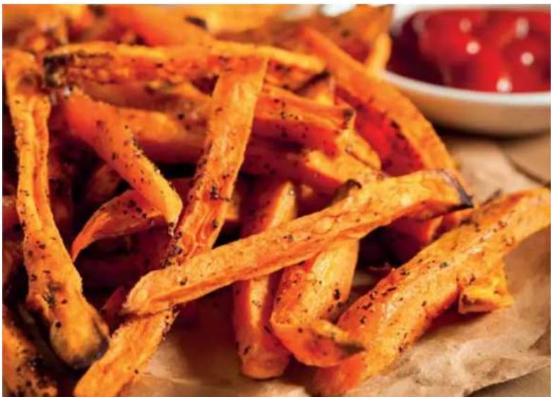 Close-up of golden-brown fried food strips on parchment paper, with a red sauce bowl in the background (no text or symbols visible)
