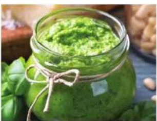 Close-up of a glass jar filled with green creamy substance tied with a rope, surrounded by fresh spinach leaves (no text or symbols visible)