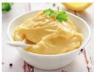 Bowl of creamy yellow food garnished with chopped green onions, served in a white bowl (no text or symbols visible)