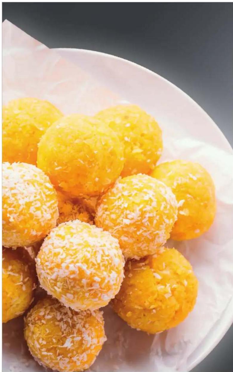 Close-up of golden-brown fried snacks topped with powdered sugar, served on a white plate (no text or symbols visible)