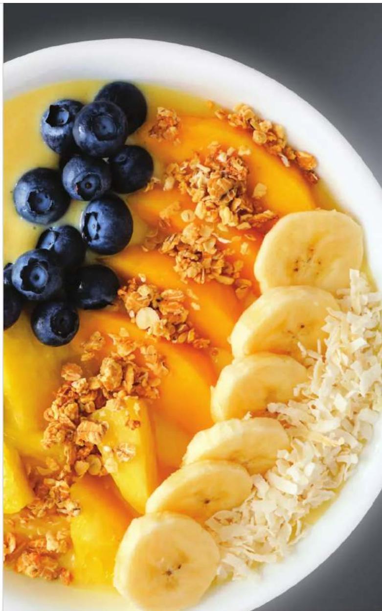 Top-down view of a colorful bowl containing blueberries, mangoes, and sliced bananas with crumbled sugar (no text or symbols visible)