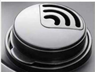 Close-up of a black and white electronic component with a circular top and internal waveform symbol (no text or labels)